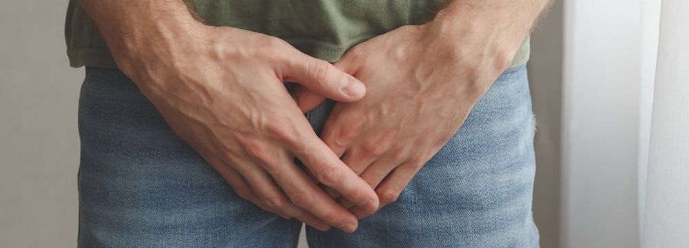 Man stands guarding his groin as he contemplates if a vasectomy is the right decision before he moves forward with treatment