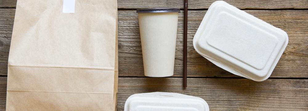 Several takeout containers including cups and bag lying across a counter