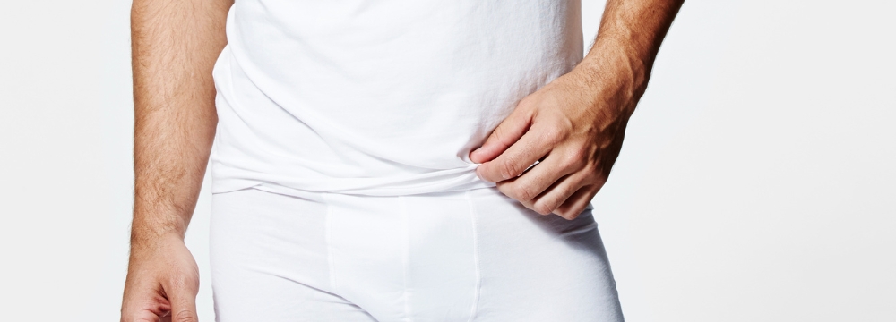 Man in white shirt and underwear with hand on hip