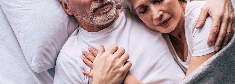 Man and woman lying together holding hands on the mans chest