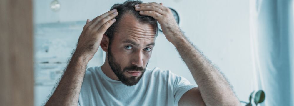 Man looking in mirror touching hair