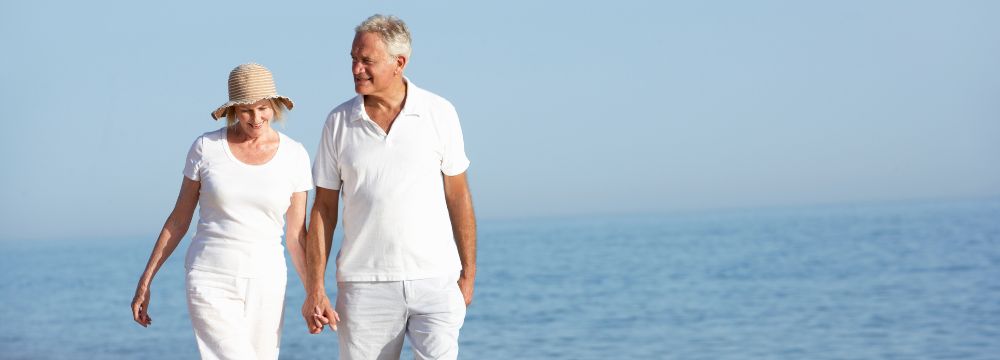 Man and wife walking on the beach holding hands