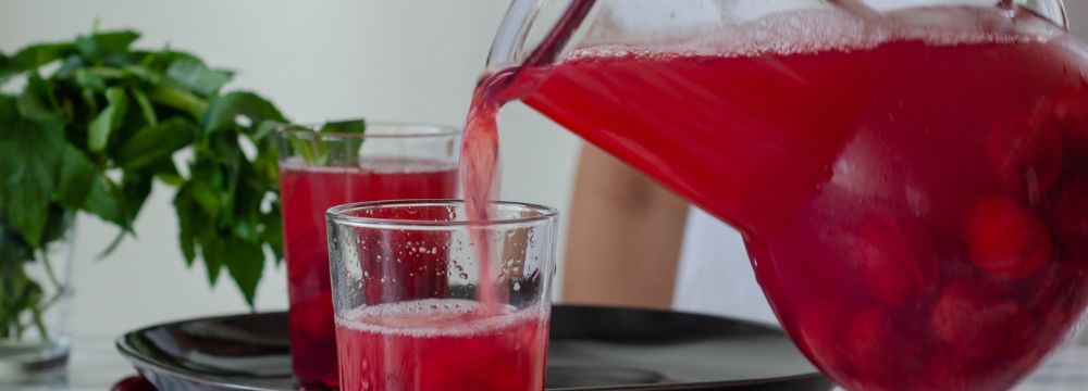 person pouring cranberry juice into glass