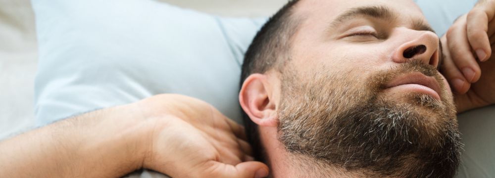 Close-up of man in bed, stretching hand behind head
